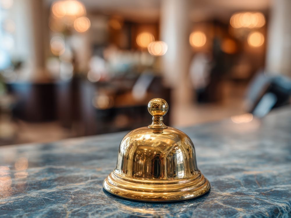 Polished brass service bell on a marble counter in a hotel lobby